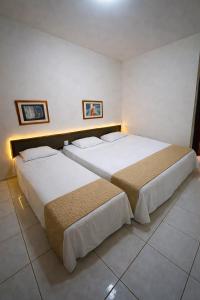two beds in a hotel room with two at Flat central com estacionamento in Ribeirão Preto +15 photos