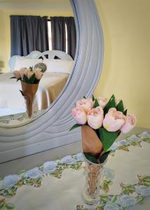 two vases with pink roses on a table in front of a mirror at Refugio Encantador in Santo Domingo