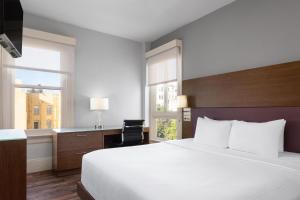 a bedroom with a bed and a desk and windows at Cartwright Hotel Union Square - BW Premier Collection in San Francisco