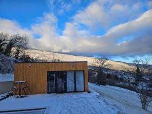 a small building in the snow with mountains in the background at Le Petit Chalet in Saint-Jorioz
