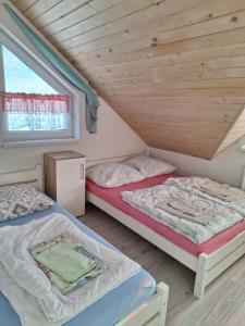 two beds in a attic bedroom with a window at Chata Lomňanka in Lomná