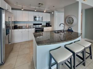 a kitchen with white cabinets and a island with bar stools at Palisade Palms TW1012 - Sea Escape in Galveston