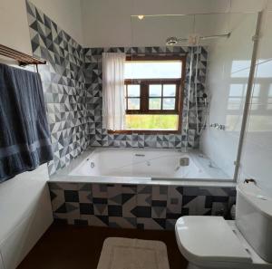 a bathroom with a tub and a toilet and a window at Chalé Bem-te-vi Vista espetacular da Serra da Mantiqueira in São José dos Campos +63 photos