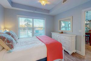a bedroom with a bed and a dresser and windows at Tranquil Harbour 102 in Mexico Beach +18 photos