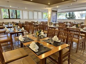 a dining room with wooden tables and chairs at Kubitschek Plaza Hotel - Flat Particular ALM in Brasília