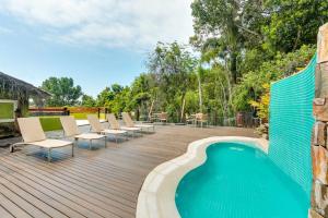a deck with chairs and a swimming pool on a house at Pousada Vila do Bosque in Bombinhas