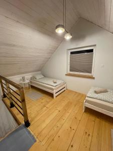 a attic room with two beds and a window at Bieszczadzkie Pola in Wańkowa