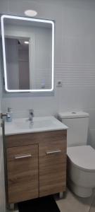 a bathroom with a sink and a toilet and a mirror at Habitación Doble con Aire cerca de la Playa in Benidorm