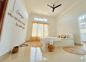 a white living room with a bed and a window at Serenyaa in Dibrugarh