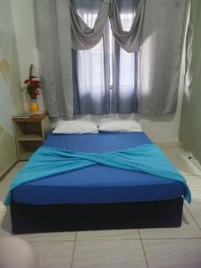a bedroom with a blue bed with a window at Kitnet Puro Dengo in São Francisco do Sul