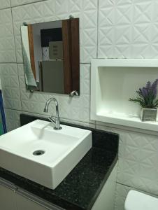 a bathroom with a white sink and a mirror at Kitnets bem localizada, próx ao autódromo! in Londrina +47 photos