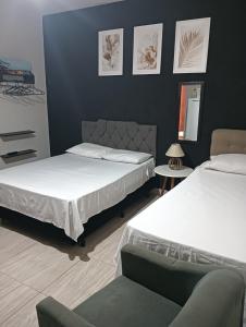 a bedroom with two beds and a chair at Kitnets bem localizada, próx ao autódromo! in Londrina