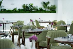 a dining room with tables and green chairs at Rauza Hotel Tashkent in Tashkent