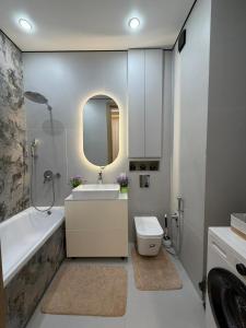 a bathroom with a sink and a toilet and a mirror at Prime Stay Almaty & VIP Apartment in the center in Almaty