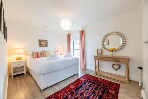 a bedroom with a white bed and a mirror and a red rug at 3 Bed in Bamburgh oc-w31886 in Bamburgh