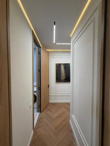 a hallway with white walls and wooden floors and a painting at Prime Stay Almaty & VIP Apartment in the center in Almaty