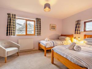a bedroom with two beds and a chair and a window at 3 Bed in Keswick oc-93590 in Threlkeld