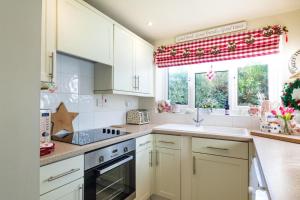 a kitchen with white cabinets and a red curtain at 2 Bed in Holt oc-2195 in Holt +6 photos