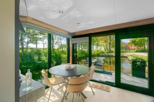a dining room with large windows and a table and chairs at Houseboats Pean-buiten Weidum in Weidum