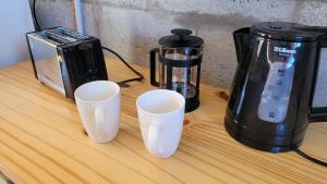 three white cups sitting on a counter next to a coffee maker at Casa Lavion in Colonia Chapadmalal +12 photos