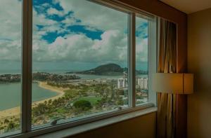a window with a view of a beach and the ocean at Sheraton Vitoria in Vitória