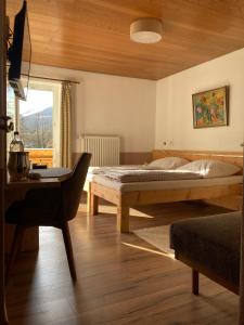 a bedroom with a bed and a desk and a window at Gästehaus Margarita in Raubling