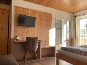 a bedroom with a desk and a television on a wall at Gästehaus Margarita in Raubling