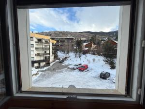 a window with a view of a parking lot with snow at Location studio à Serre Chevalier 1350 in Saint-Chaffrey