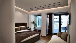 a bedroom with a bed and a couch and windows at Fivenco Suites - Private Suites w King Bed Modern in Tirana