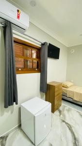 a room with a bed and a television and a white box at Pousada Jabuticabeira in Jaguaruna