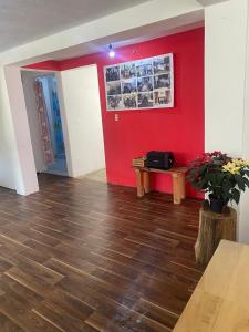 a room with a red wall and a table and flowers at Casa Ecológica Angangueo in Mineral de Angangueo