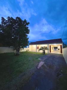 a house with a tree in front of a yard at Casa da lagoa in Imbituba