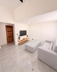 a white living room with a white couch and a tv at Brianne's Place in Playa hermosa