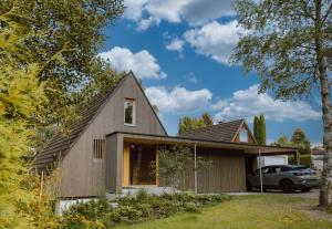 a barn style house with a car parked in the yard at HEIMATEL - A Huesle in Oberreute