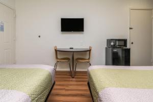 a room with two beds and a table and a tv at Motel 6 Fort Worth, TX - North in Fort Worth +28 photos