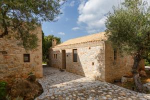 a stone building with a tree in front of it at Tzokeika Traditional Settlement in Riglia