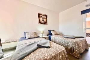 two beds in a room with a picture on the wall at Oasis Penthouse Maspalomas in Maspalomas