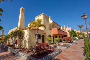 a building with a palm tree in front of it at Tagoro Family & Fun Costa Adeje in Adeje
