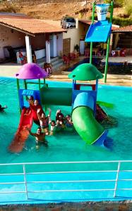 a group of children playing on a water slide in a pool at Chalés Lampião in Piranhas