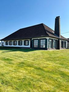 a large house with a grass field in front of it at 't Reigergoed in Ichtegem