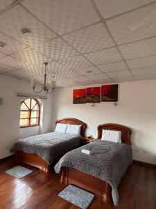 two beds in a bedroom with a ceiling at Casa La Ronda in Quito
