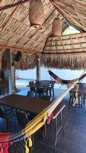 a table and chairs under a straw roof at Anuk Glamping in San Bernardo del Viento