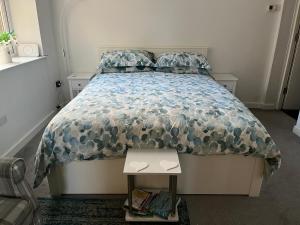 a bedroom with a bed with a comforter and a table at Flat 2 Frank Lewis House in Hay-on-Wye