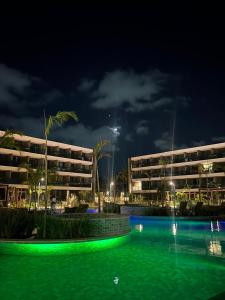 a swimming pool in front of a hotel at night at Beach Class Verano Flat 216 C in Porto De Galinhas