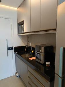 a kitchen with a sink and a microwave at Beach Class Verano Flat 216 C in Porto De Galinhas