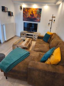 a living room with a brown couch and a flat screen tv at Große Auszeit Eifel mit Sauna, Kamin und Terrasse in Nettersheim