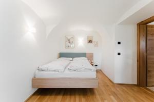 a bedroom with a bed with white walls and wooden floors at Gut Pecketsberg in Oepping