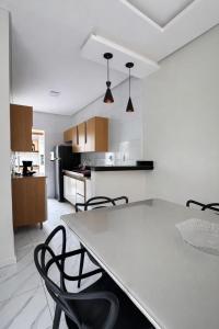 a white kitchen with a table and chairs in it at Casa 3 Quartos Ar Condicionado , Area de Churrasco in Petrolina