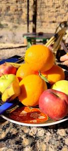 a plate of fruit on a table with apples and oranges at Auberge IMIN TAGHYA in Akhendachou nʼAït Ouffi