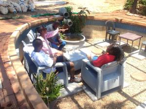 a group of people sitting in chairs in a yard at Palm Terrace Guesthouse in Durban